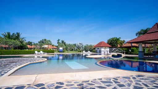 Expansive outdoor swimming pool with surrounding lounge chairs and cabana in a sunny residential setting