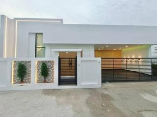 Modern white single-storey house with illuminated entrance and fence