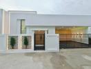 Modern white single-storey house with illuminated entrance and fence