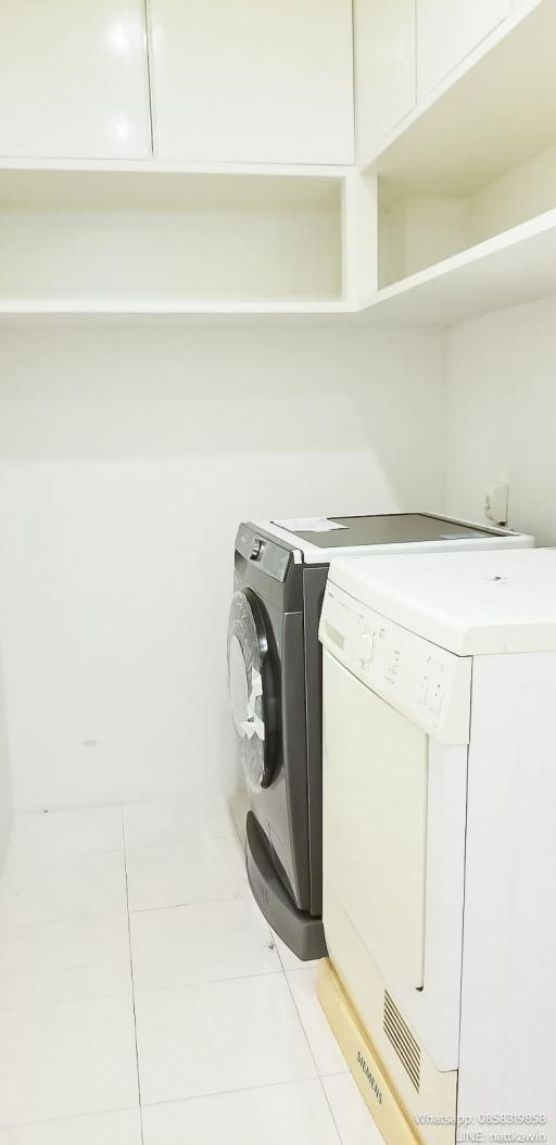 Compact laundry room with modern appliances and ample shelving