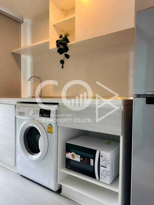 Modern kitchen with white washing machine and microwave