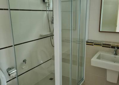 Modern bathroom with glass shower enclosure, white sink, and toilet