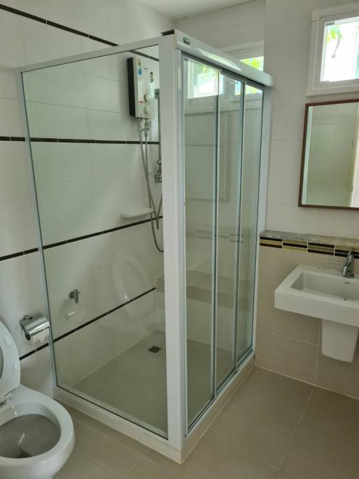Modern bathroom with glass shower enclosure, white sink, and toilet