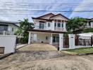 Spacious two-story house with a large driveway and a clear blue sky