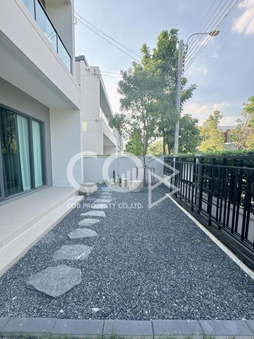 Modern house exterior with gravel path and lush greenery