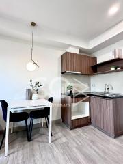 Modern kitchen with dining area - white table, dark chairs, wooden cabinetry, and pendant lighting