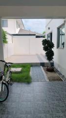 Paved pathway leading towards a residential backyard with well-maintained grass and bike