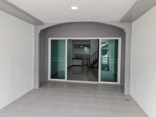 Modern entrance with gray tiles leading to a bright, open-concept kitchen