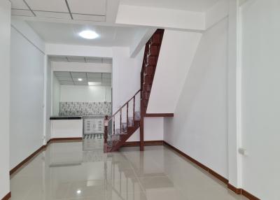 Spacious interior view showing staircase, kitchen area, and tiled flooring