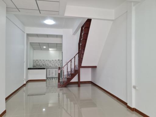 Spacious interior view showing staircase, kitchen area, and tiled flooring