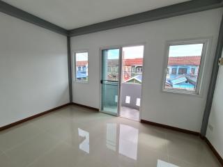 Bright bedroom with tile flooring, large windows, and glass door leading to balcony