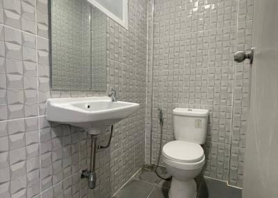 Compact tiled bathroom with wall-mounted sink and toilet