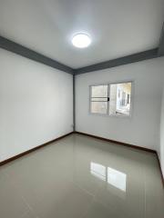 Empty bedroom with glossy floor tiles and a large window