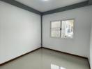 Empty bedroom with glossy floor tiles and a large window