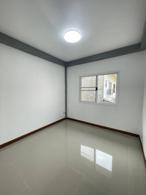 Empty bedroom with glossy floor tiles and a large window