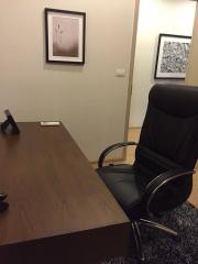 Home office with a wooden desk, executive chair, and framed art on walls