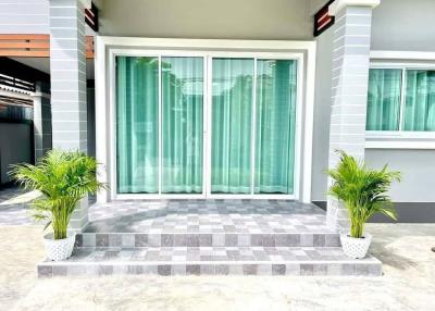 Modern house front with large sliding glass doors and decorative plants