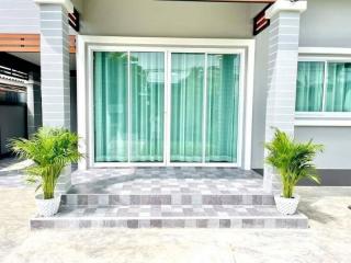 Modern house front with large sliding glass doors and decorative plants