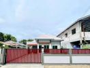 Exterior view of a modern single-story house with a gated fence