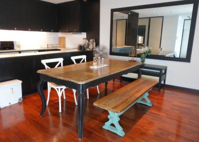 Modern kitchen with wooden dining table, hardwood floors, and black cabinetry