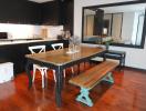 Modern kitchen with wooden dining table, hardwood floors, and black cabinetry