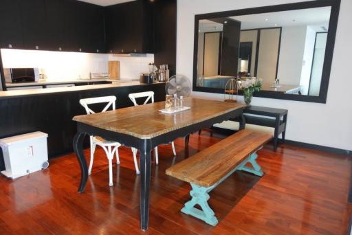 Modern kitchen with wooden dining table, hardwood floors, and black cabinetry