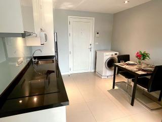 Modern kitchen with dining area featuring stainless steel appliances and front load washer