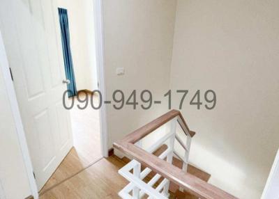 White staircase and landing area with wooden flooring