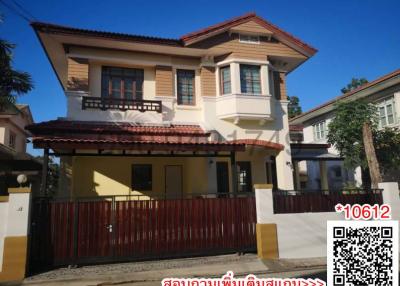 Two-story residential house with a gated entrance and balcony under a blue sky