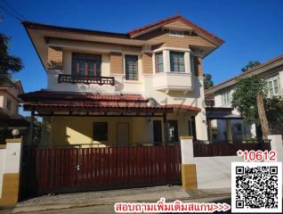 Two-story residential house with a gated entrance and balcony under a blue sky