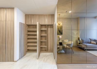 Elegant entrance area with wooden shelves, sliding door, and a glimpse into the dining and living space