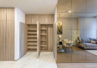 Elegant entrance area with wooden shelves, sliding door, and a glimpse into the dining and living space