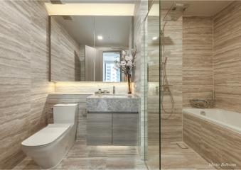 Modern bathroom with natural stone tiles, glass shower, and bathtub