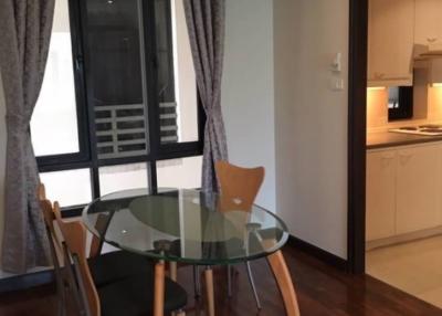 Compact dining area adjacent to kitchen with glass table and wooden chairs