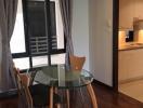 Compact dining area adjacent to kitchen with glass table and wooden chairs