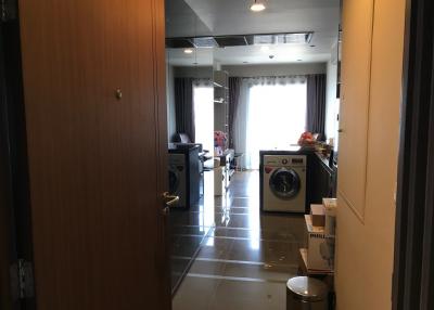 Interior view of an apartment showing the entrance to a laundry area and a blurred view of a living space background