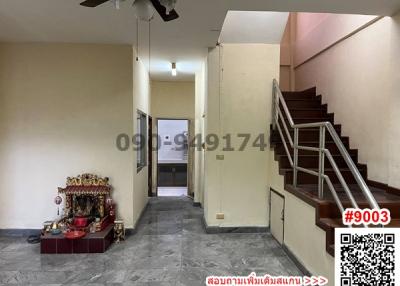 Interior view of a house showing a staircase, entrance door, and hall area