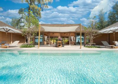 Luxurious outdoor pool area with adjacent lounge and dining space with modern furnishings under a canopy