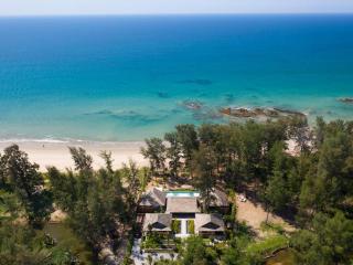 Aerial view of a beachfront property with clear blue waters and surrounding greenery