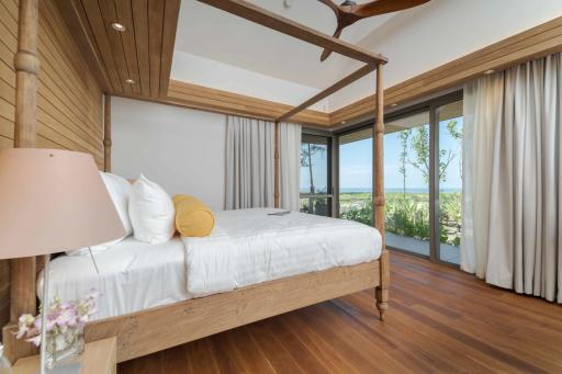 Spacious bedroom with a four-poster bed, hardwood floors, and ocean view