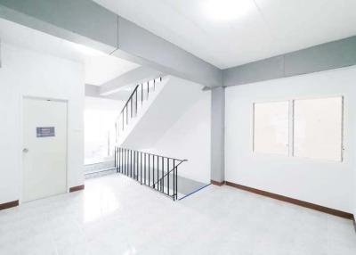 Spacious and well-lit empty living space with staircase and windows