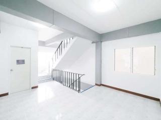 Spacious and well-lit empty living space with staircase and windows