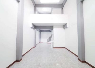 Spacious white corridor in building with tiled flooring and bright lighting