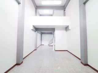 Spacious white corridor in building with tiled flooring and bright lighting