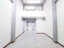 Spacious white corridor in building with tiled flooring and bright lighting