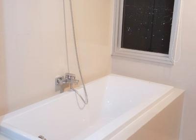 Modern white bathtub with shower fixture and window