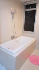 Modern white bathtub with shower fixture and window