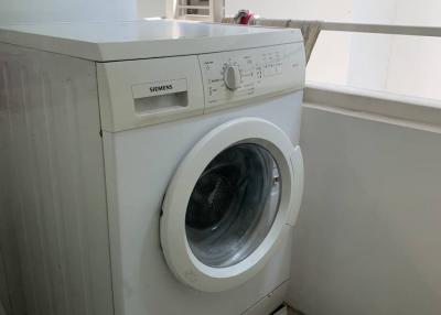 Siemens front-loading washing machine in a small laundry area