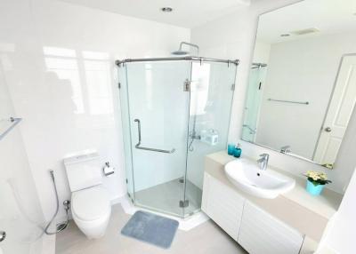 Modern white bathroom with glass shower enclosure and ample natural light