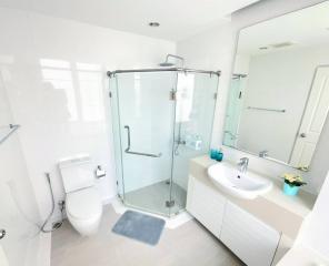 Modern white bathroom with glass shower enclosure and ample natural light